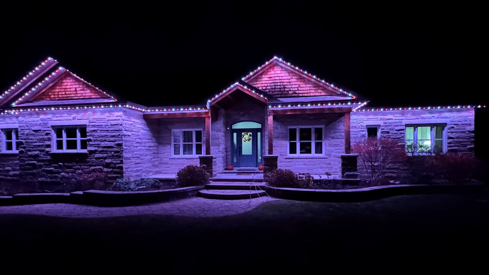 Stone bungalow with permanent lights along every gable and eave at night