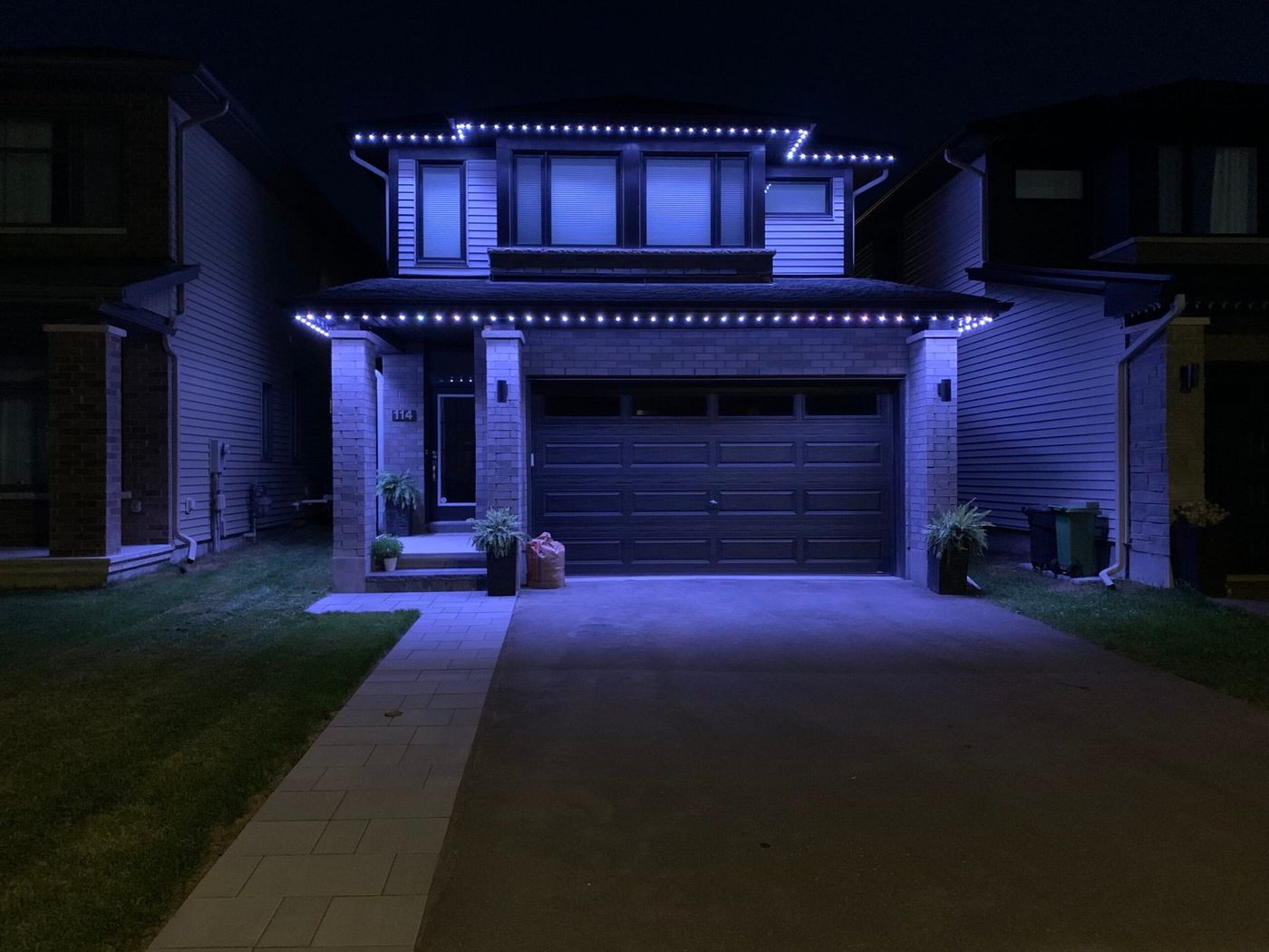 Modern two-storey home with blue permanent lights along the roofline and porch