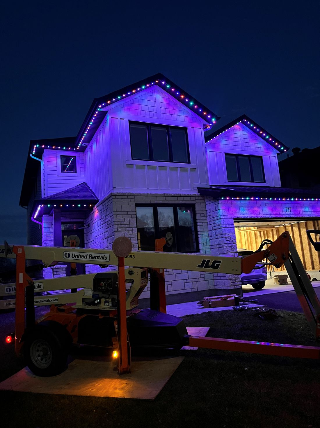 New-build home glowing purple with multicolour lights along both gables
