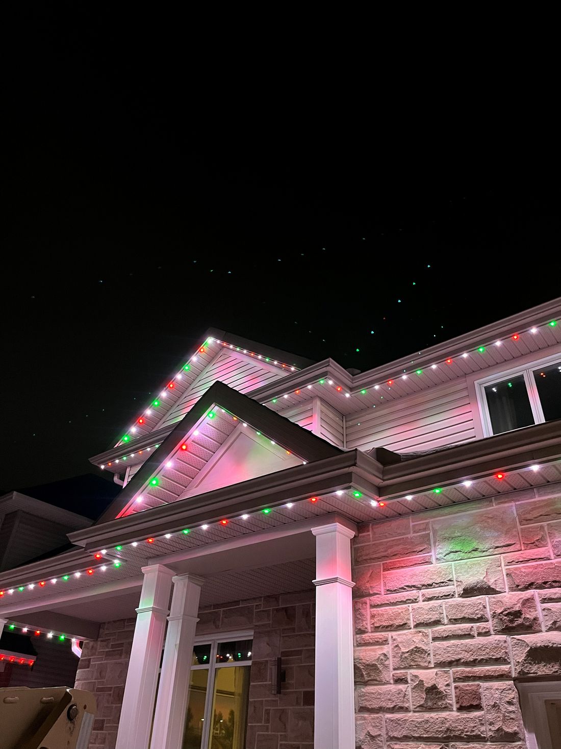 Close-up of red, green and white lights evenly spaced under a porch roofline